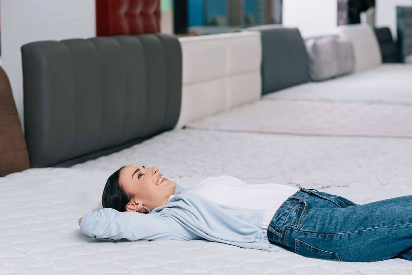 side view of smiling customer lying on orthopedic mattress in furniture store