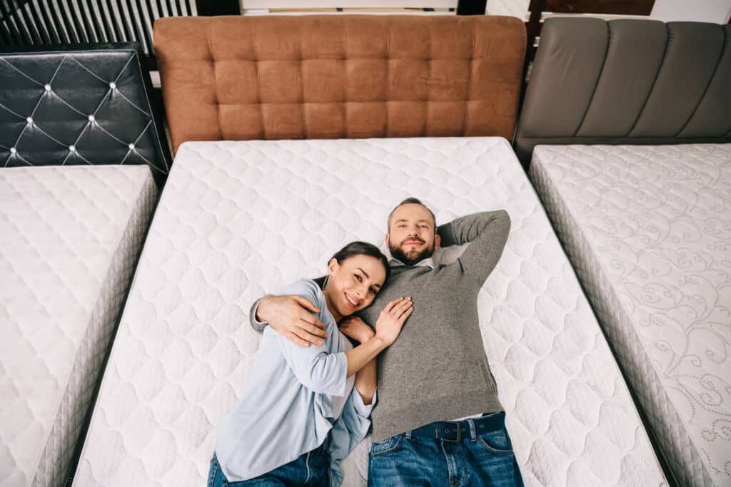 overhead-view-of-smiling-couple-lying-on-bed-in-fu-2022-12-16-19-02-44-utc.jpg