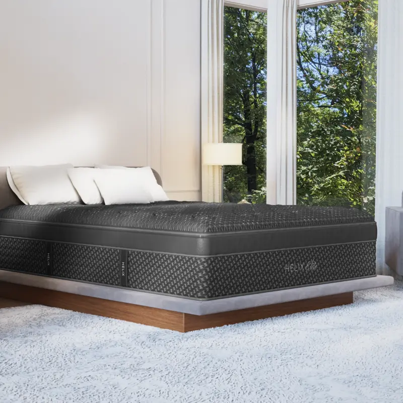 Helix Midnight Elite premium hybrid mattress on a stylish bed, featuring a cooling cover and zoned lumbar support, in a bright room with large windows and soft rug.