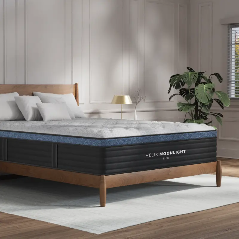 Helix Moonlight Luxe mattress on a wooden bed frame, featuring plush top, GlacioTex™ cooling cover, and stylish bedroom setting with decorative plants and modern lighting.