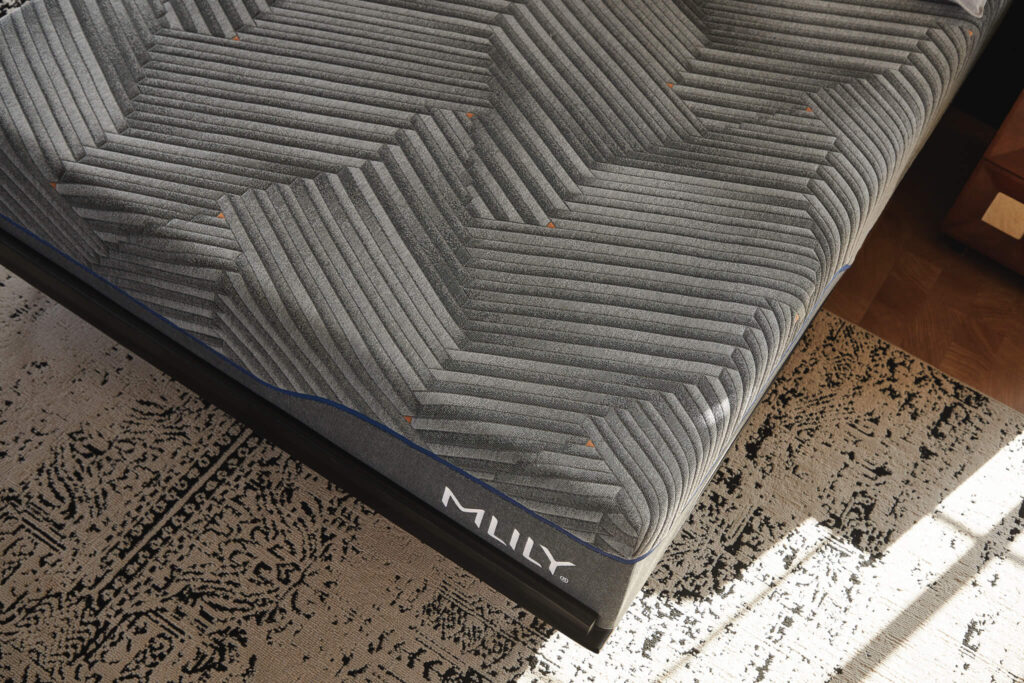 MLILY hybrid mattress showcasing advanced foam technology and unique hexagonal design, placed on a stylish rug in a modern bedroom setting.