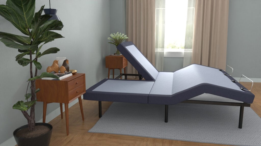 Adjustable bed base in modern bedroom setting, featuring elevated head and foot sections, surrounded by decorative plant and wooden furniture.